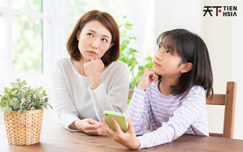 Mother and daughter looking up with hand below their chin while thinking
