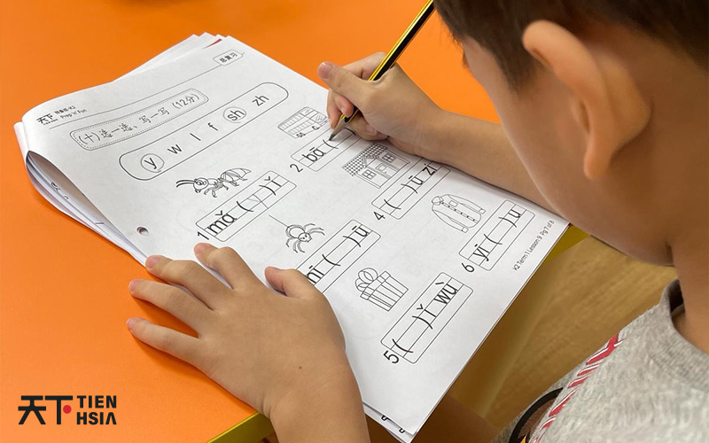 Person writing on a sheet of paper with chinese characters