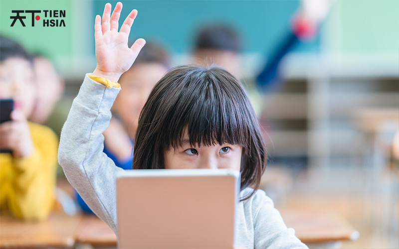 Child raising their hand in tuition