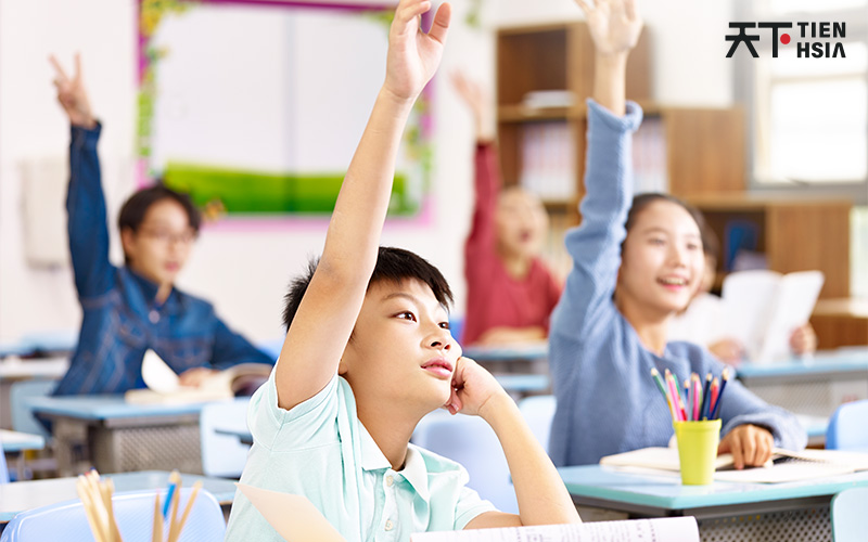 Engaged primary students raising hands in Chinese class