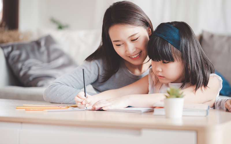 Mother guiding daughter during Chinese second language tuition session.