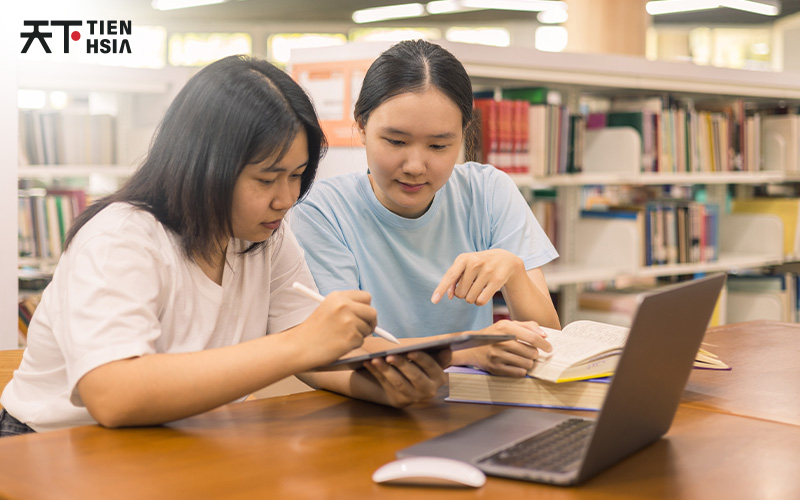 Two students studying together in a library at Tien Hsia.